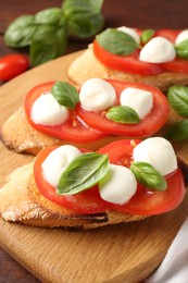 Photo of Tasty sandwiches with mozzarella cheese, tomatoes and basil on table, closeup