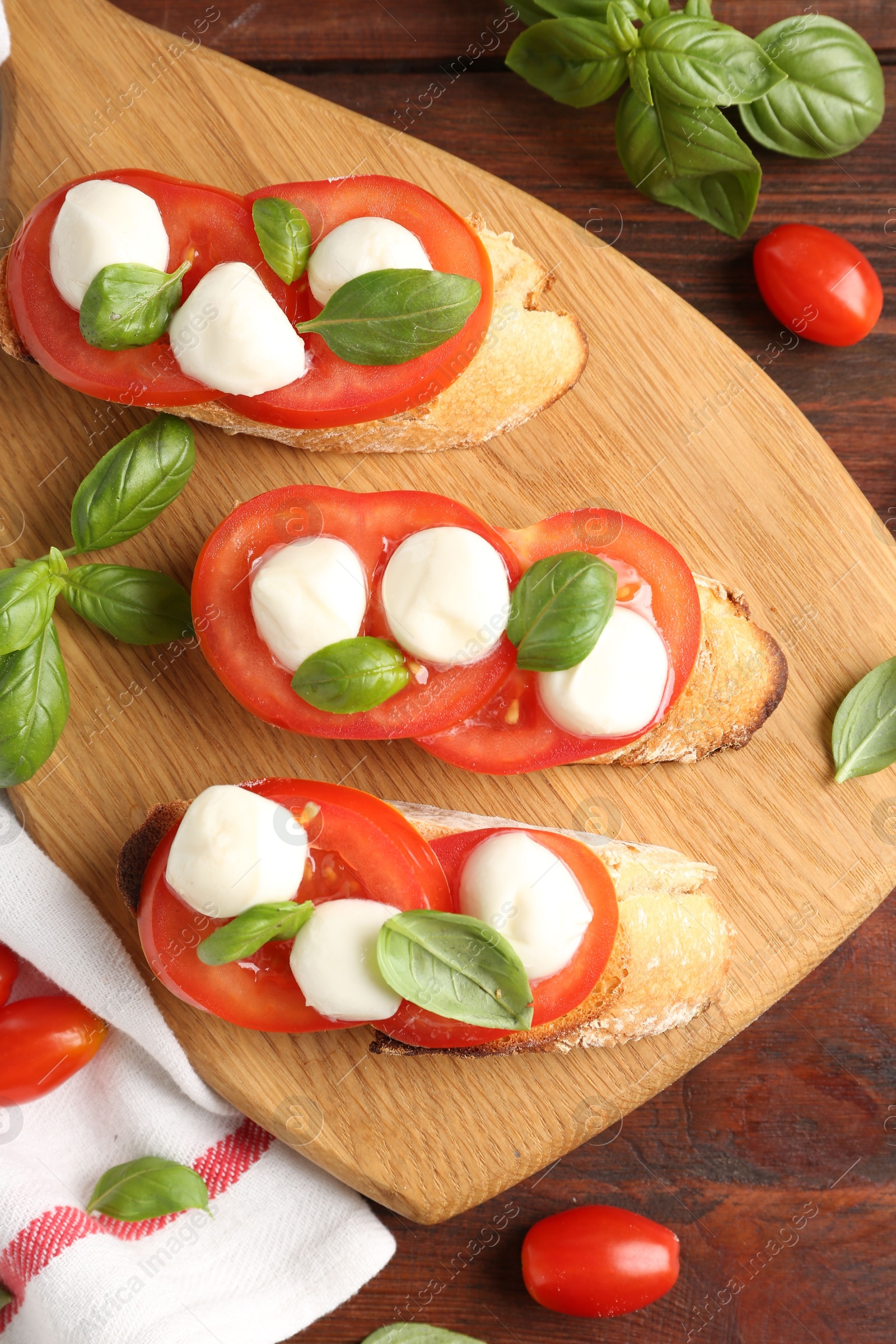 Photo of Tasty sandwiches with mozzarella cheese, tomatoes and basil on wooden table, flat lay