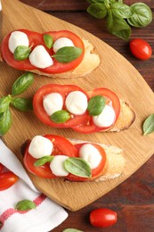 Photo of Tasty sandwiches with mozzarella cheese, tomatoes and basil on wooden table, flat lay