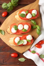 Photo of Tasty sandwiches with mozzarella cheese, tomatoes and basil on wooden table, flat lay