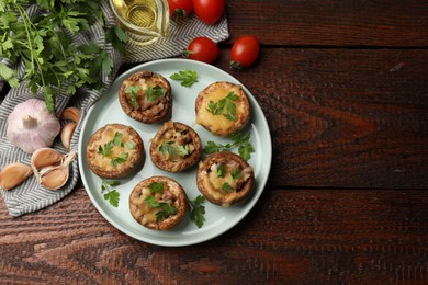 Photo of Tasty stuffed mushrooms and ingredients on wooden table, flat lay. Space for text