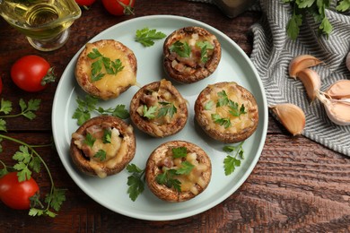 Photo of Tasty stuffed mushrooms and ingredients on wooden table, flat lay