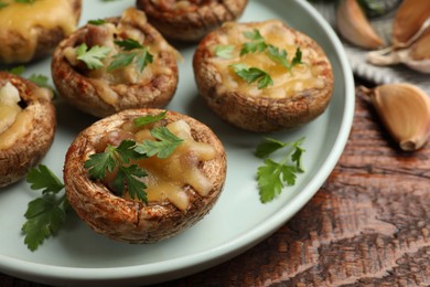 Photo of Tasty stuffed mushrooms on wooden table, closeup