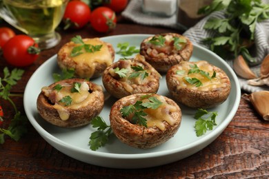 Photo of Tasty stuffed mushrooms and ingredients on wooden table, closeup