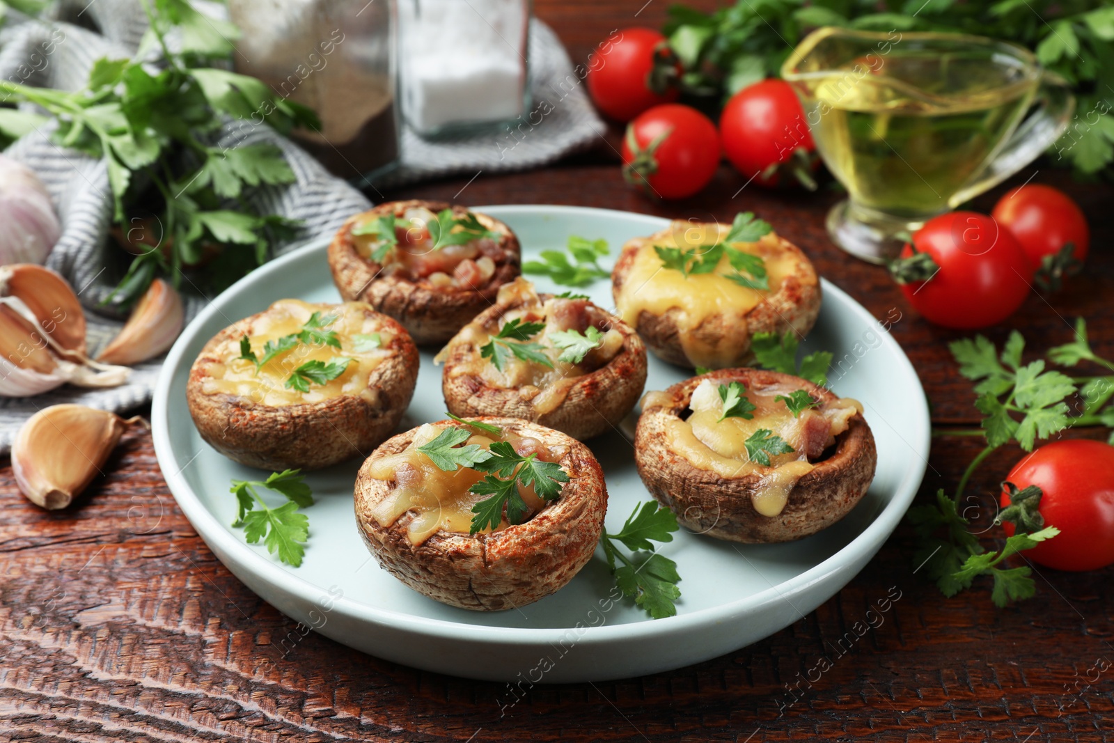 Photo of Tasty stuffed mushrooms and ingredients on wooden table, closeup