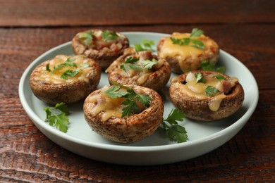 Photo of Tasty stuffed mushrooms on wooden table, closeup