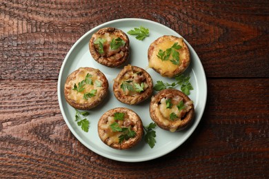 Photo of Tasty stuffed mushrooms on wooden table, top view