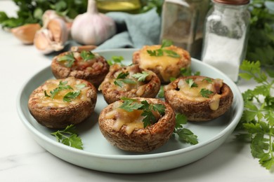 Photo of Tasty stuffed mushrooms and spices on white marble table, closeup