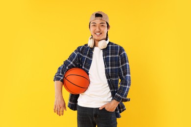 Photo of Student with headphones and basketball ball on orange background