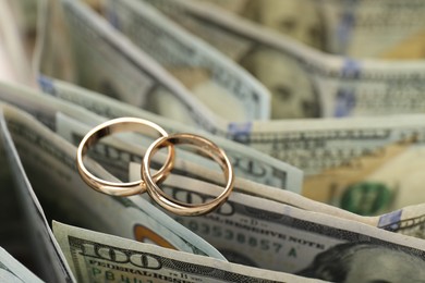 Photo of Gold wedding rings and dollar banknotes, closeup. Space for text