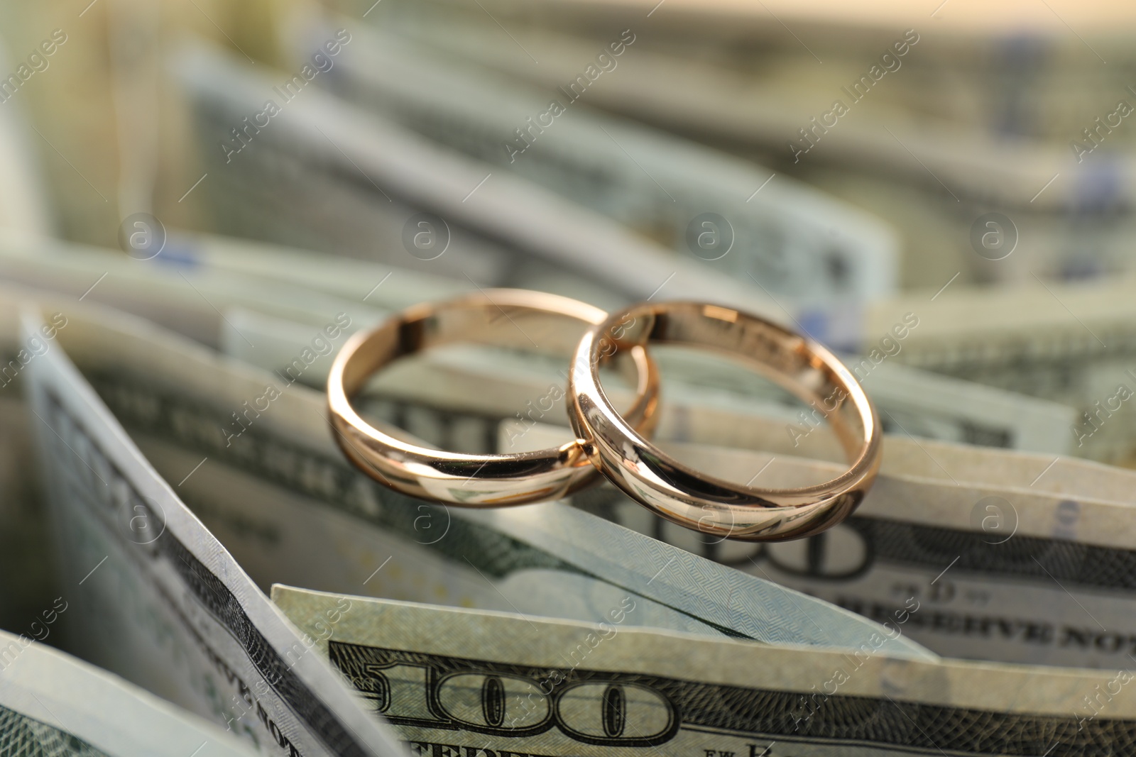 Photo of Gold wedding rings and dollar banknotes, closeup
