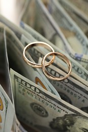 Photo of Gold wedding rings and dollar banknotes on table, closeup