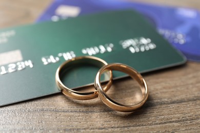 Photo of Gold wedding rings and credit cards on wooden table, closeup