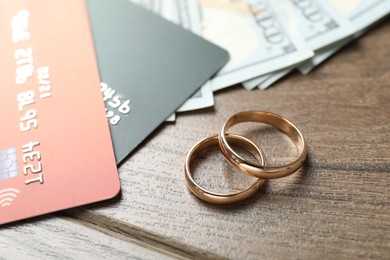 Photo of Gold wedding rings and credit cards on wooden table, closeup