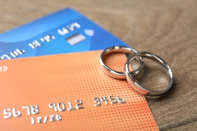 Photo of Silver wedding rings and credit cards on wooden table, closeup