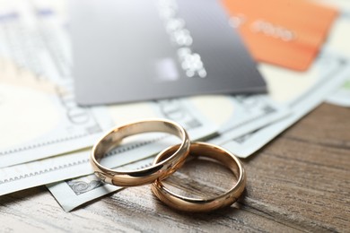 Photo of Gold wedding rings and credit cards on wooden table, closeup