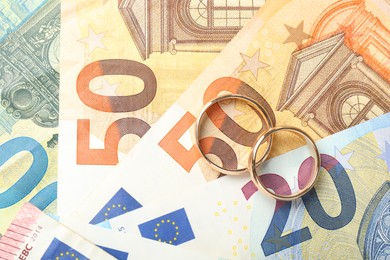 Photo of Gold wedding rings and euro banknotes, top view. Space for text