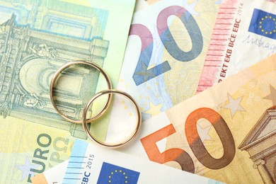 Photo of Gold wedding rings and euro banknotes, top view. Space for text