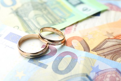 Photo of Gold wedding rings and euro banknotes, closeup. Space for text