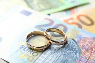 Photo of Gold wedding rings and euro banknotes, closeup