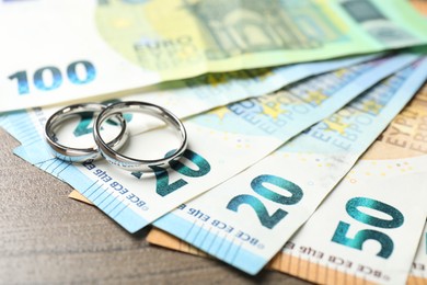 Photo of Silver wedding rings and euro banknotes on wooden table, closeup