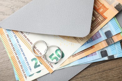 Photo of Silver wedding rings, envelope and euro banknotes on wooden table, flat lay