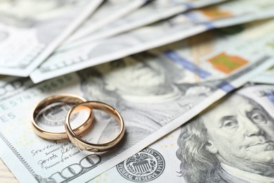 Photo of Gold wedding rings and dollar banknotes, closeup. Space for text