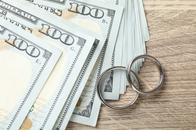 Photo of Silver wedding rings and dollar banknotes on wooden table, flat lay