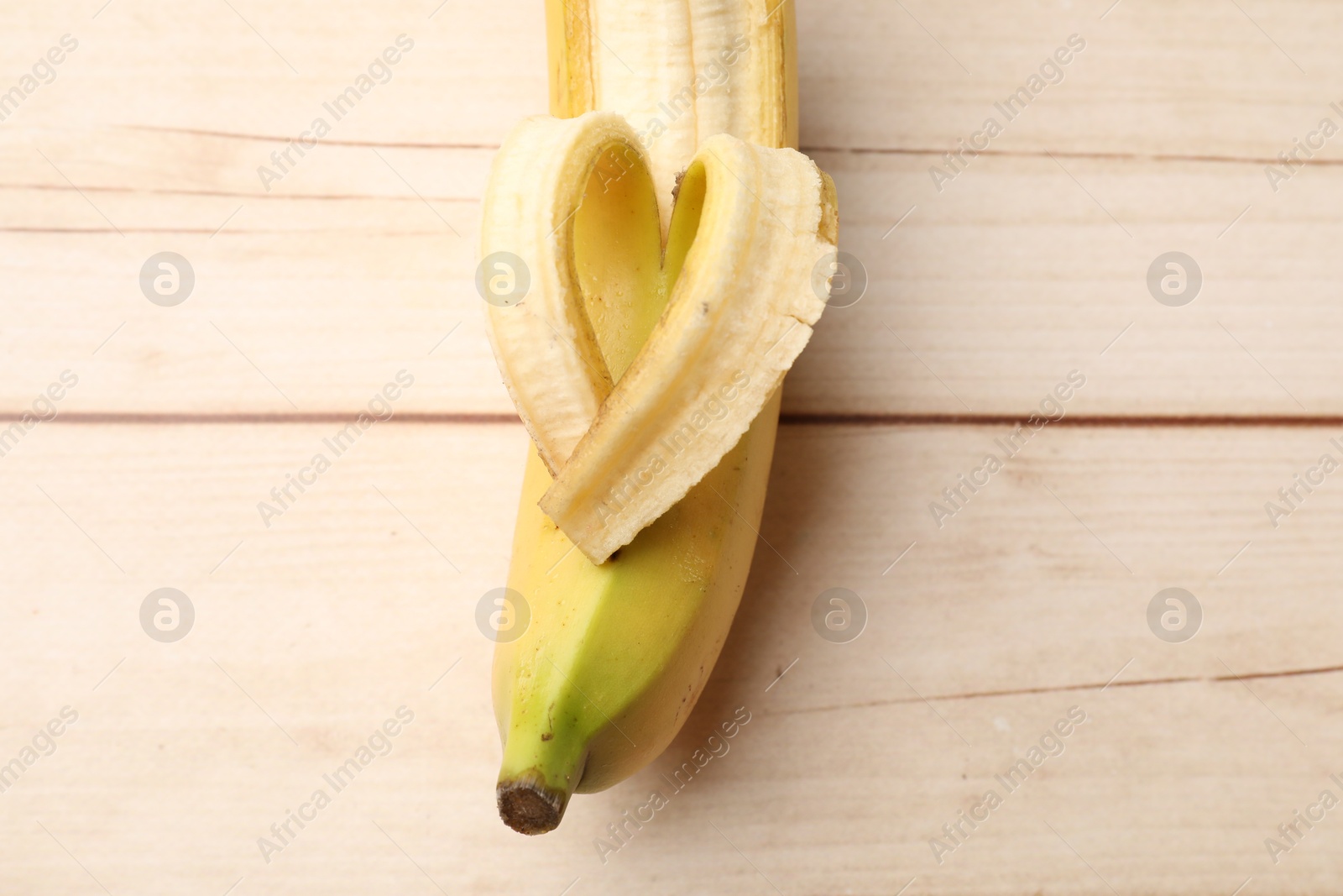 Banana with heart made of peel on wooden table, top view Photo of Banana with heart made of peel on wooden table, top view