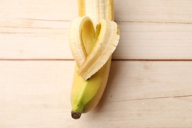 Photo of Banana with heart made of peel on wooden table, top view