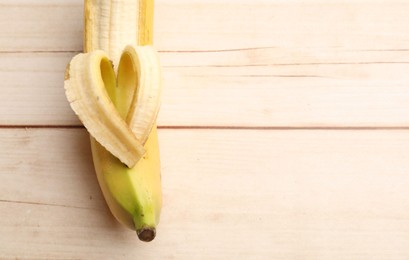 Photo of Banana with heart made of peel on wooden table, top view. Space for text