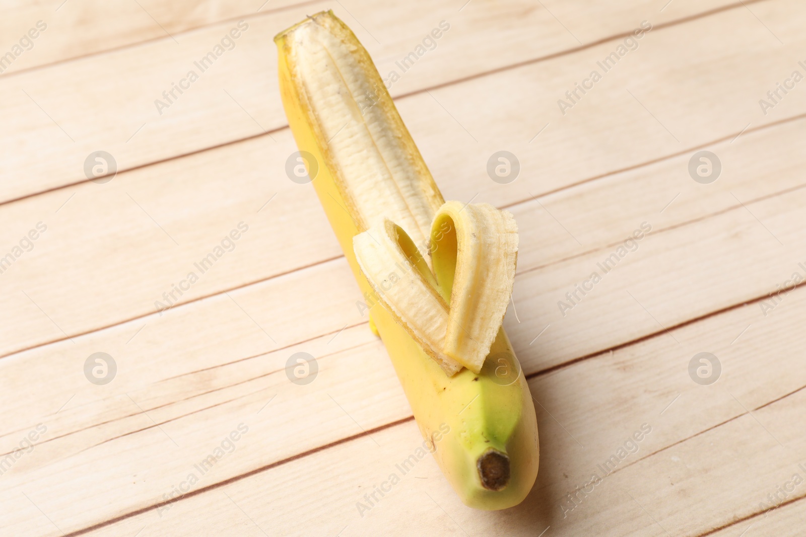 Banana with heart made of peel on wooden table, above view Photo of Banana with heart made of peel on wooden table, above view