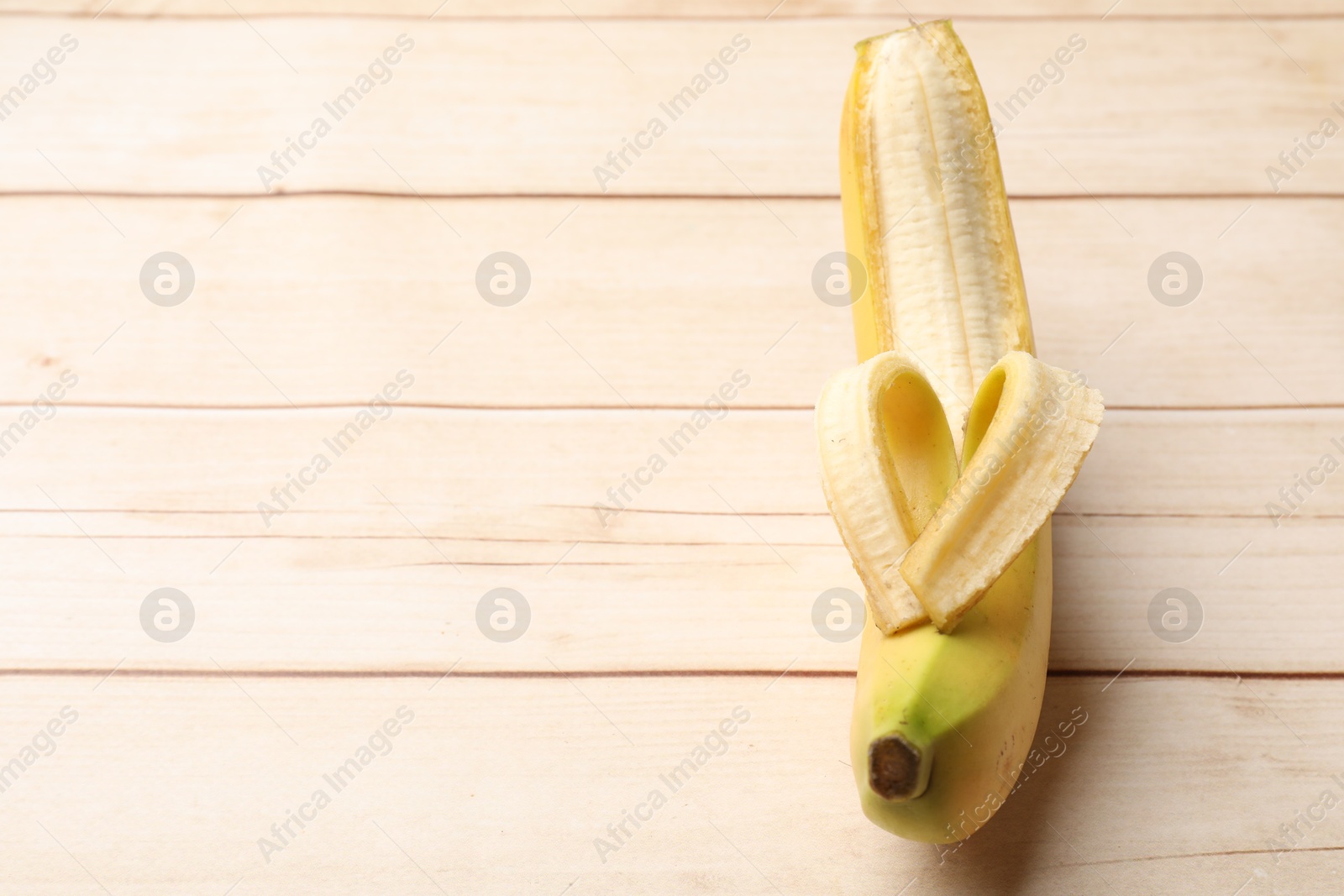 Banana with heart made of peel on wooden table, above view. Space for text Photo of Banana with heart made of peel on wooden table, above view. Space for text