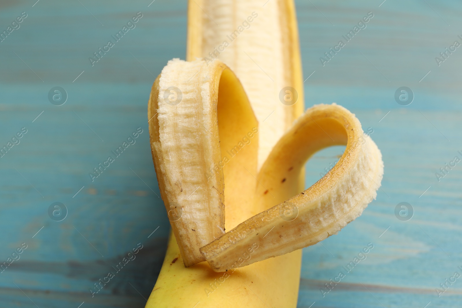 Banana with heart made of peel on light blue wooden table, closeup Photo of Banana with heart made of peel on light blue wooden table, closeup