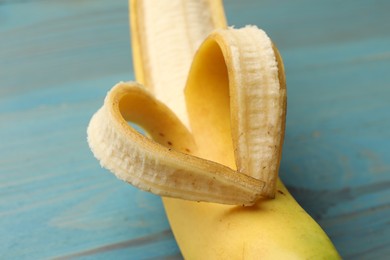 Photo of Banana with heart made of peel on light blue wooden table, closeup