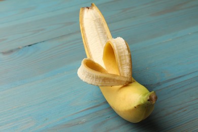 Photo of Banana with heart made of peel on light blue wooden table, closeup. Space for text
