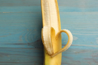 Photo of Banana with heart made of peel on light blue wooden table, top view