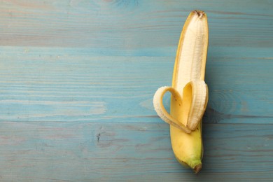 Photo of Banana with heart made of peel on light blue wooden table, top view. Space for text