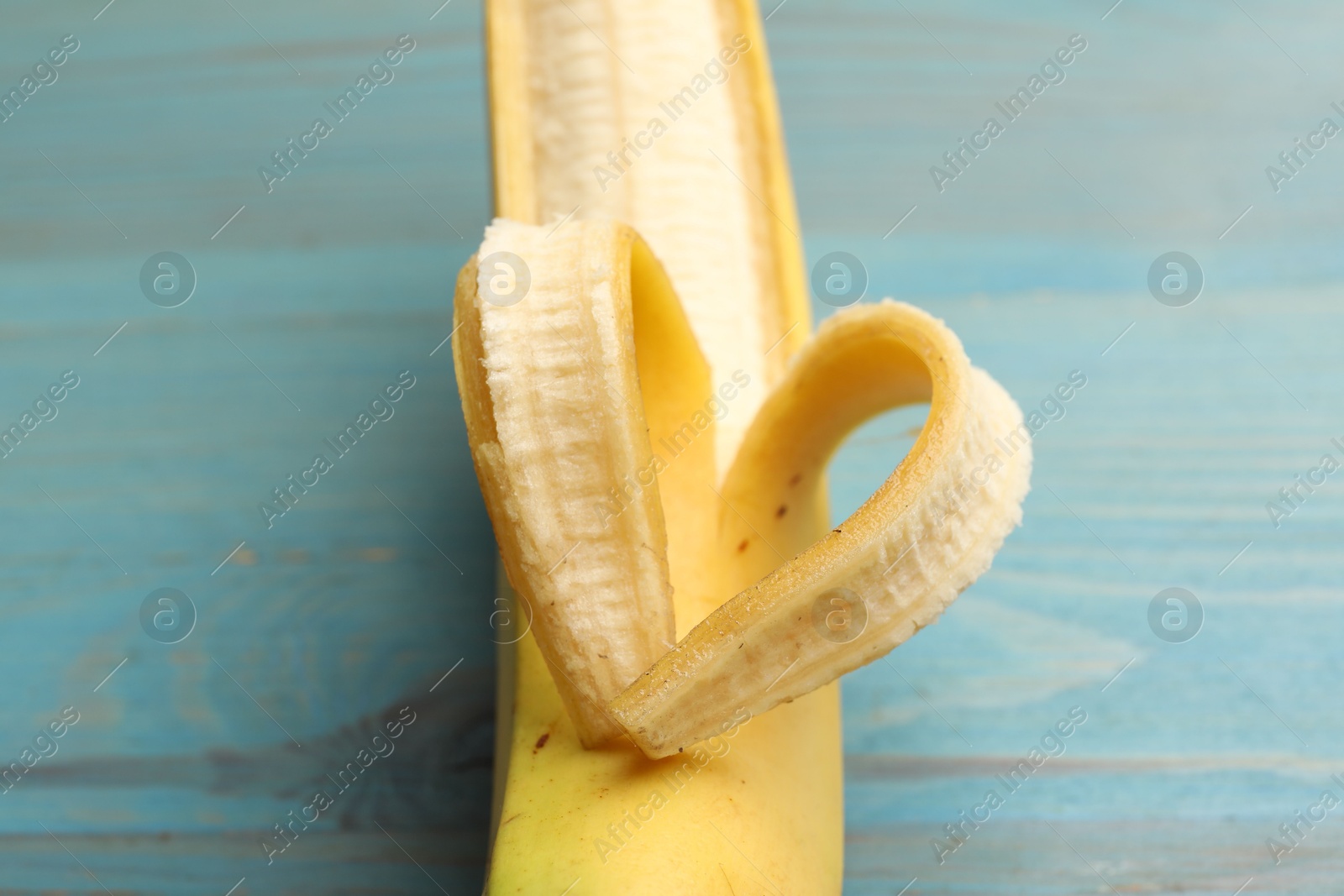 Banana with heart made of peel on light blue wooden table, closeup Photo of Banana with heart made of peel on light blue wooden table, closeup