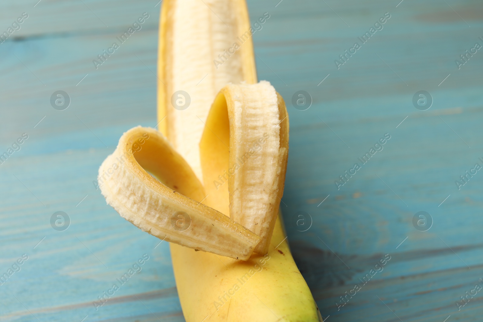 Banana with heart made of peel on light blue wooden table, closeup Photo of Banana with heart made of peel on light blue wooden table, closeup