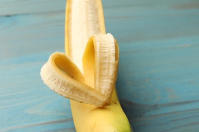 Photo of Banana with heart made of peel on light blue wooden table, closeup