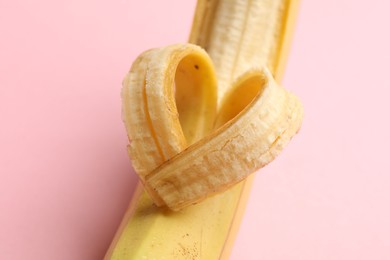Photo of Banana with heart made of peel on pink background, closeup