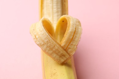 Photo of Banana with heart made of peel on pink background, closeup