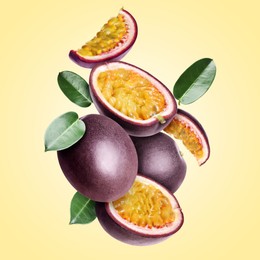 Image of Delicious ripe passion fruits and green leaves falling on pale yellow gradient background