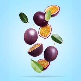 Image of Delicious ripe passion fruits with green leaves falling on light blue background