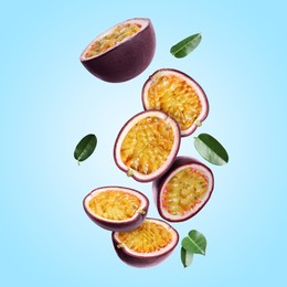 Image of Delicious cut passion fruits with green leaves falling on light blue background