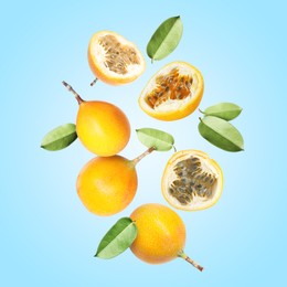 Image of Delicious ripe passion fruits with green leaves falling on light blue background