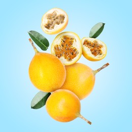 Image of Delicious ripe passion fruits with green leaves falling on light blue background