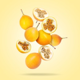 Image of Delicious ripe passion fruits falling on pale yellow gradient background