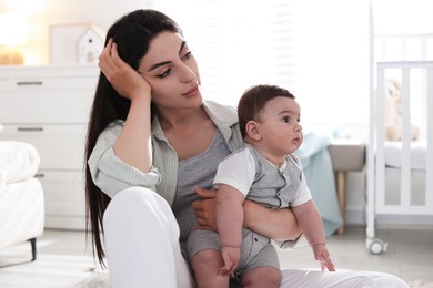 Photo of Woman suffering from postpartum depression with her little baby at home
